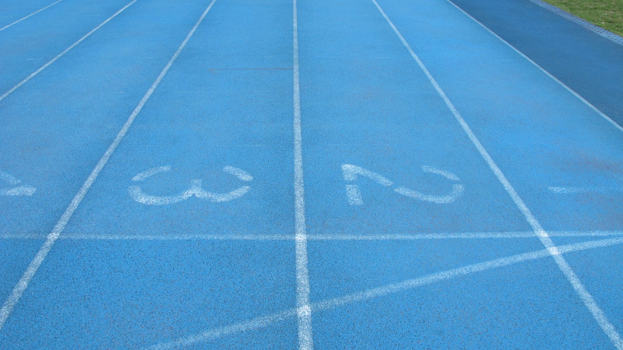 Close-up view of a blue athletics track with white lane numbers and markings.